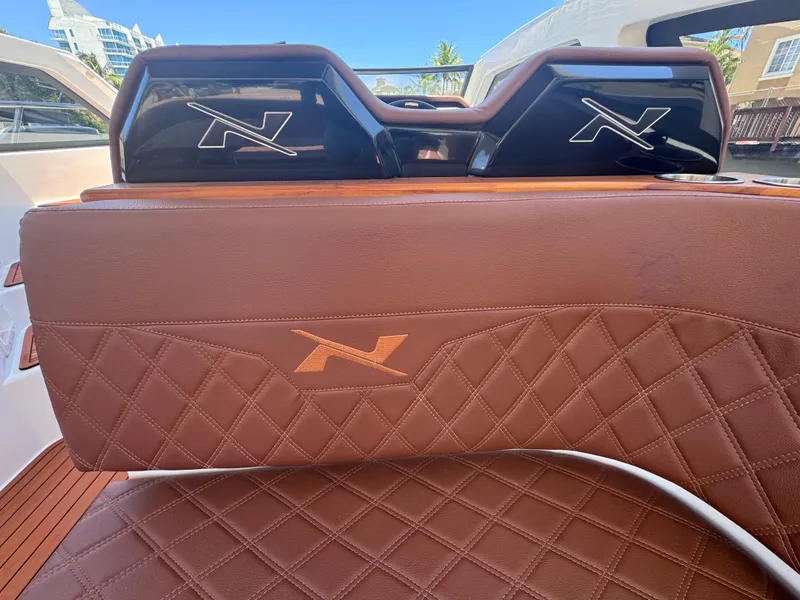Slide: The Image of 2024 NX Boats 340 Sport Coupe interior with brown quilted leather seats and logo detailing. - 39