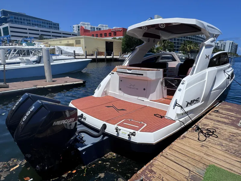 Slide: The Image of 2024 NX Boats 340 Sport Coupe docked, showcasing sleek design and powerful Mercury outboard engine. - 4