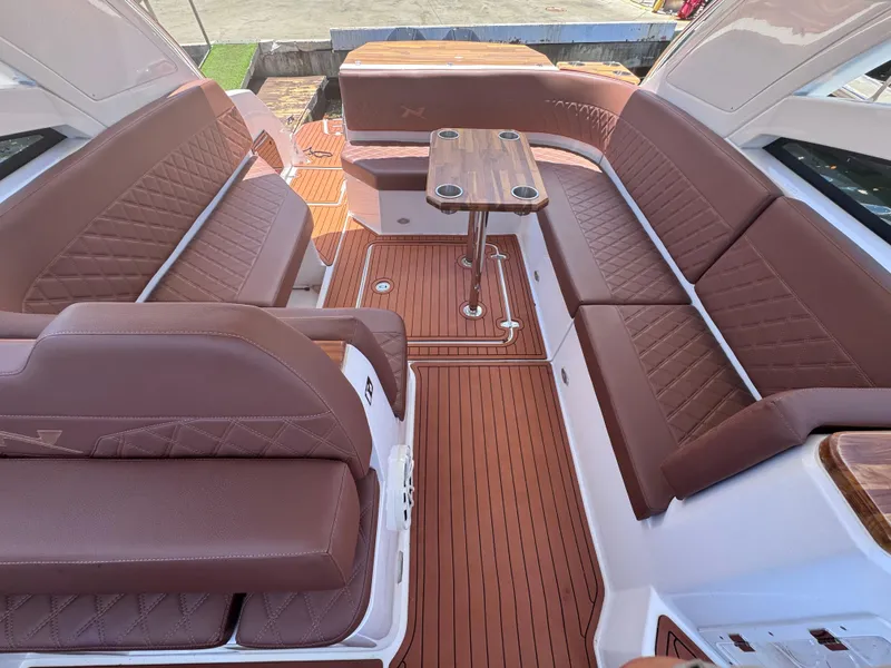 Slide: The Image of 2024 NX Boats 340 Sport Coupe interior with brown leather seating and wooden flooring. - 42