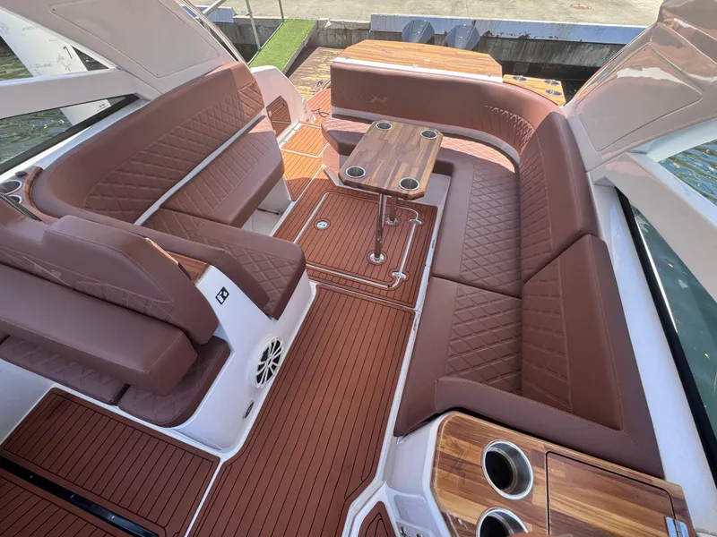 Slide: The Image of 2024 NX Boats 340 Sport Coupe interior with luxurious brown seating and wooden accents. - 43