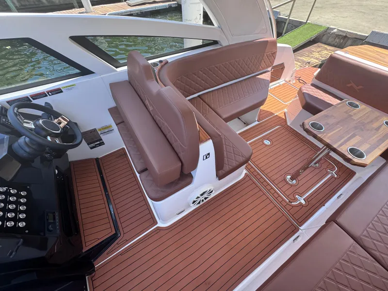 Slide: The Image of 2024 NX Boats 340 Sport Coupe interior with brown seating and wooden flooring. - 44