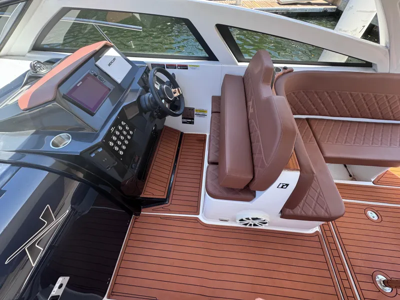 Slide: The Image of 2024 NX Boats 340 Sport Coupe interior with brown leather seating and modern dashboard. - 45
