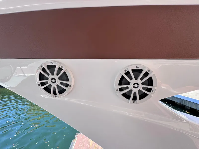 Slide: The Image of 2024 NX Boats 340 Sport Coupe speakers on sleek exterior by the water. - 48