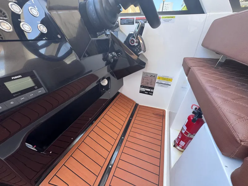 Slide: The Image of 2024 NX Boats 340 Sport Coupe cockpit with brown seating, wooden flooring, and control panel. - 49
