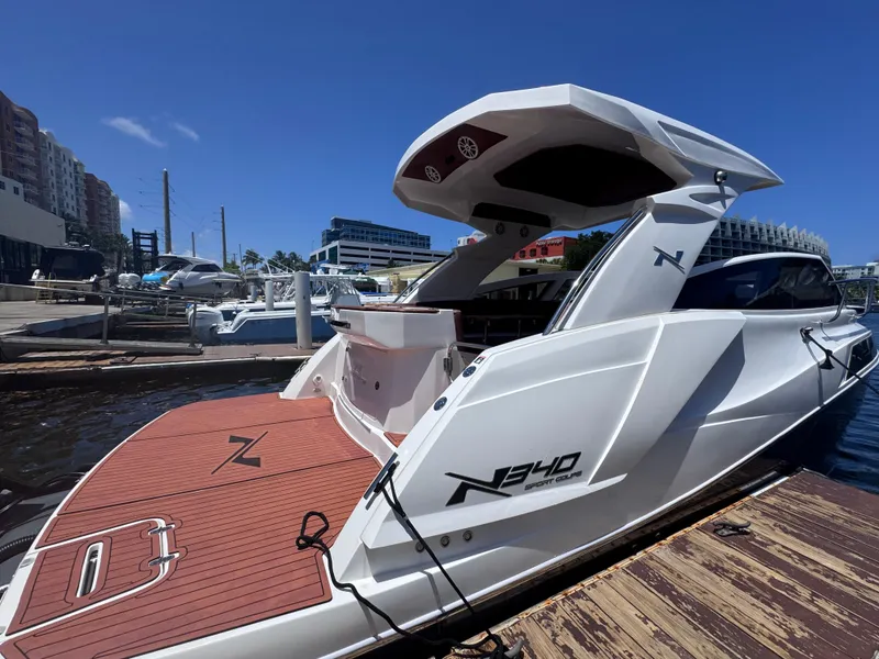 Slide: The Image of 2024 NX Boats 340 Sport Coupe docked at a marina under clear blue skies. - 6