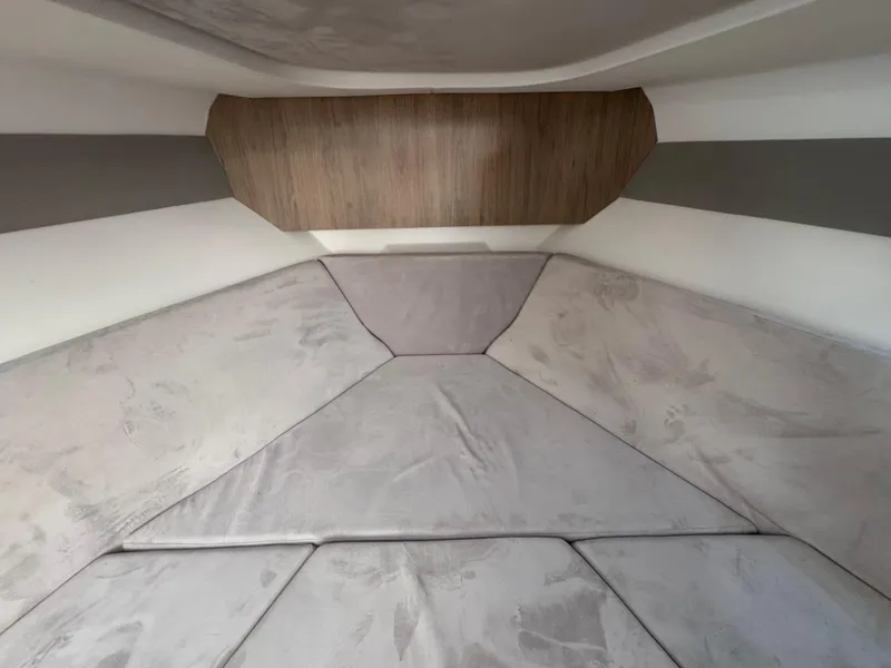 Slide: The Image of 2024 NX Boats 340 Sport Coupe interior cabin with cushioned seating and wood accents. - 85