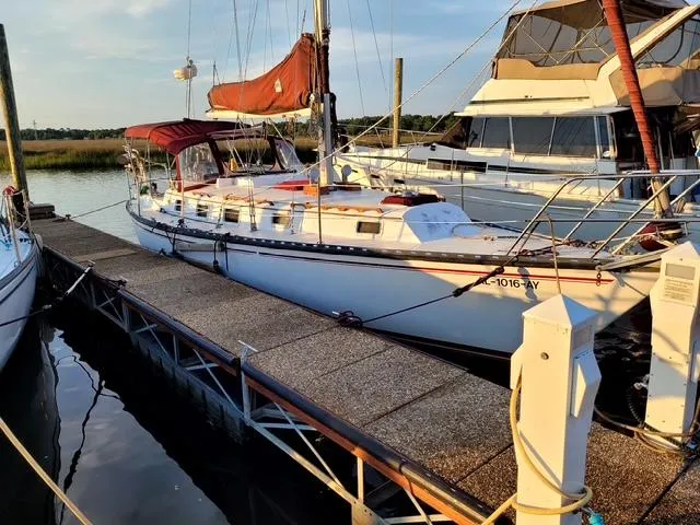 The Image of 1984 Endeavour 33 sailboat docked at marina, featuring red sails and white hull. - 0