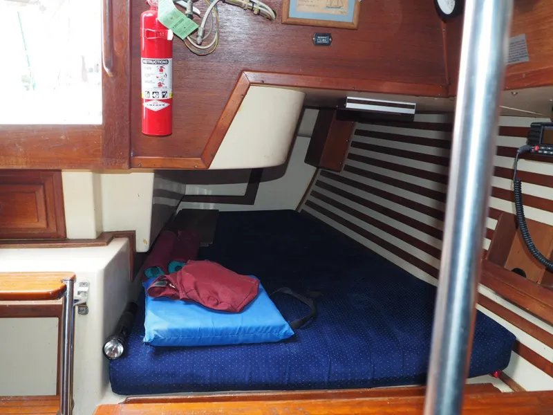 Slide: The Image of 1984 Endeavour 33 sailboat cabin interior with bed, fire extinguisher, and wooden accents. - 16