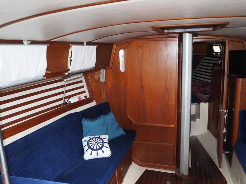 Slide: The Image of 1984 Endeavour 33 yacht interior with wooden paneling, blue seating, and nautical decor. - 19