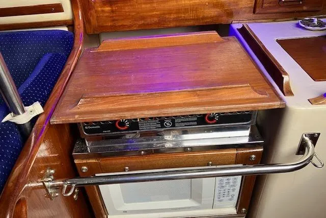 Slide: The Image of 1984 Endeavour 33 yacht kitchen with stove and microwave, featuring wooden cabinetry. - 26