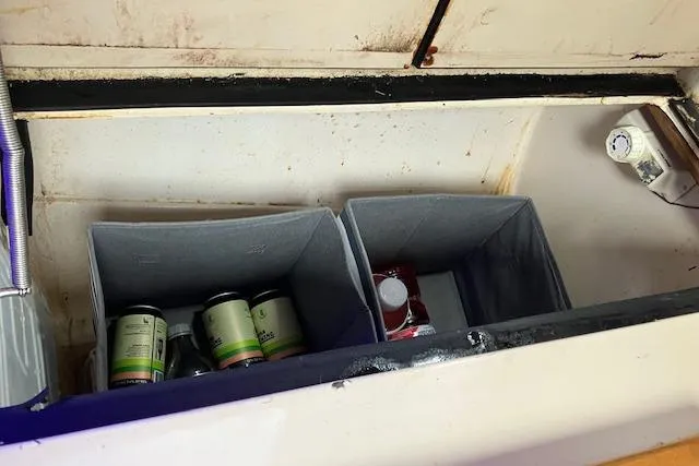 Slide: The Image of Storage compartment in 1984 Endeavour 33 boat with organized containers and canned goods. - 27