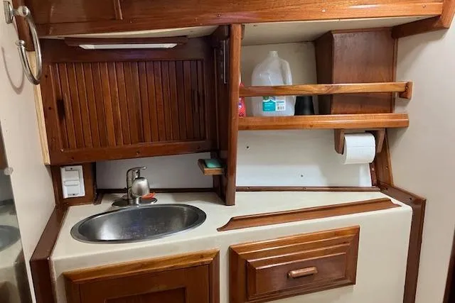 Slide: The Image of 1984 Endeavour 33 yacht galley with wooden cabinets, sink, and storage shelves. - 29