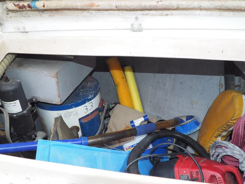 Slide: The Image of Storage compartment of 1984 Endeavour 33 boat with various tools and equipment. - 34