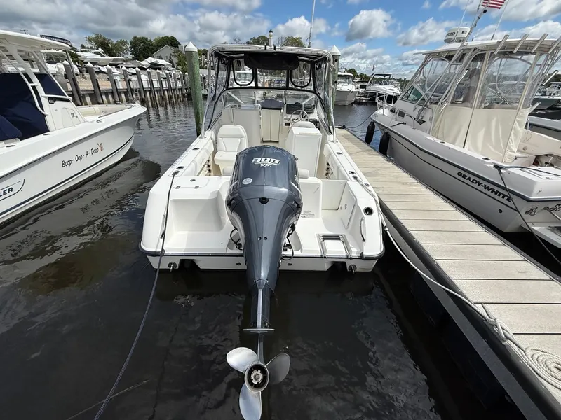 Slide: The Image of Edgewater 245 CX 2012 boat docked with outboard motor, surrounded by other boats. - 2