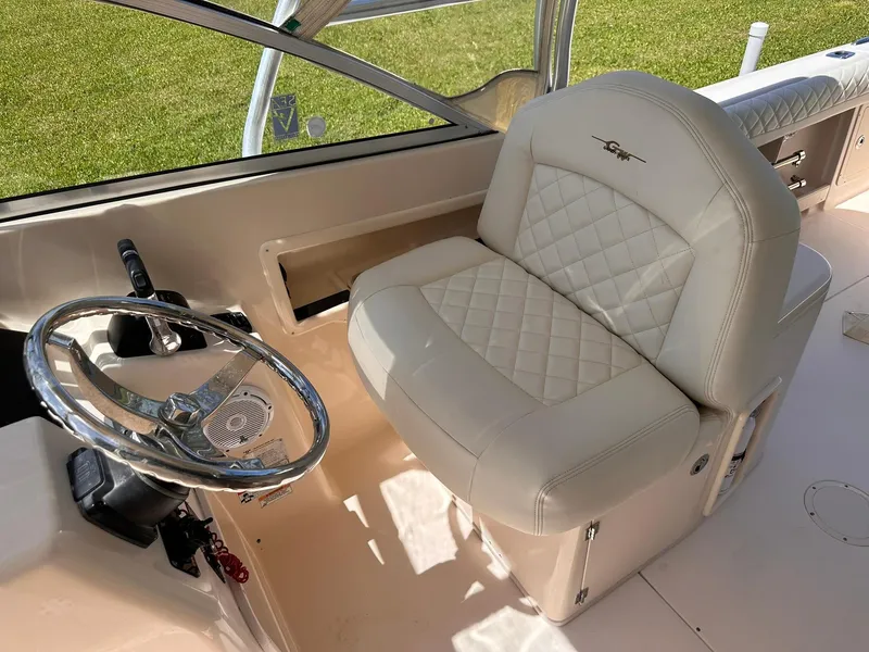 Slide: The Image of Captain's seat and steering wheel of 2011 Grady-White Freedom 275 boat, featuring luxurious upholstery. - 20