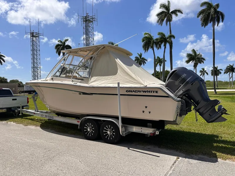 Slide: The Image of 2011 Grady-White Freedom 275 boat on trailer, parked near palm trees under a clear blue sky. - 36