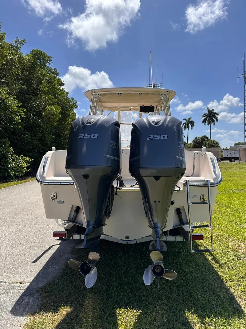 Slide: The Image of 2011 Grady-White Freedom 275 boat with dual 250 horsepower engines, parked on grass. - 4