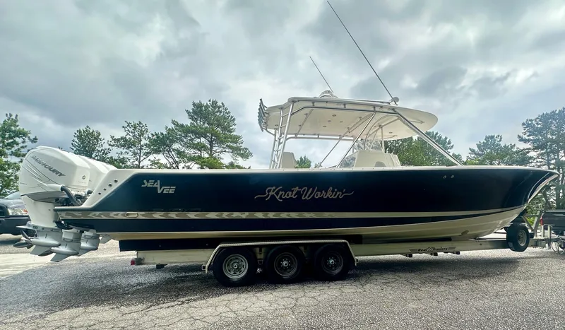 Slide: The Image of 2008 SeaVee 390B boat on trailer, dark hull, triple engines, overcast sky. - 3