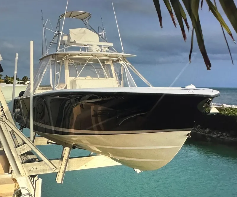 Slide: The Image of 2008 SeaVee 390B boat on lift, docked by turquoise water, under cloudy sky. - 6