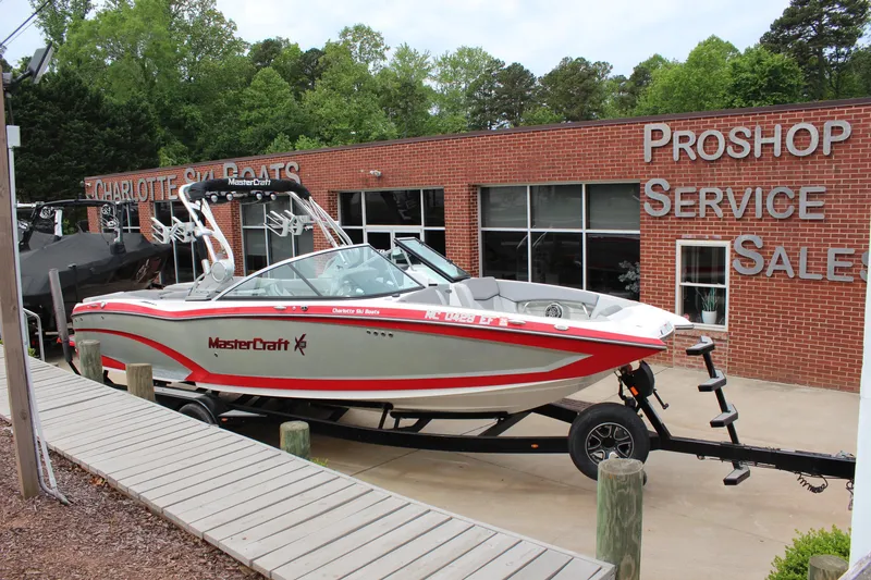 The Image of 2016 MasterCraft X26 boat on trailer outside a pro shop and service center. - 1