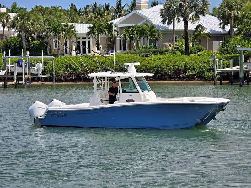 The Image of 2023 Caymas 30 CT boat cruising on a scenic waterway near a coastal home. - 1