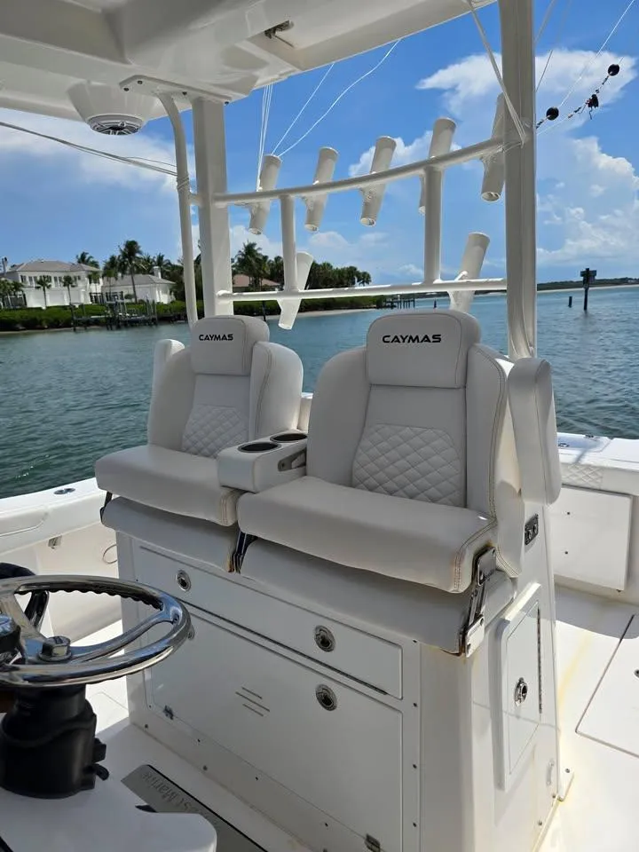 Slide: The Image of 2023 Caymas 30 CT boat interior with luxurious seating and rod holders, docked by the water. - 14