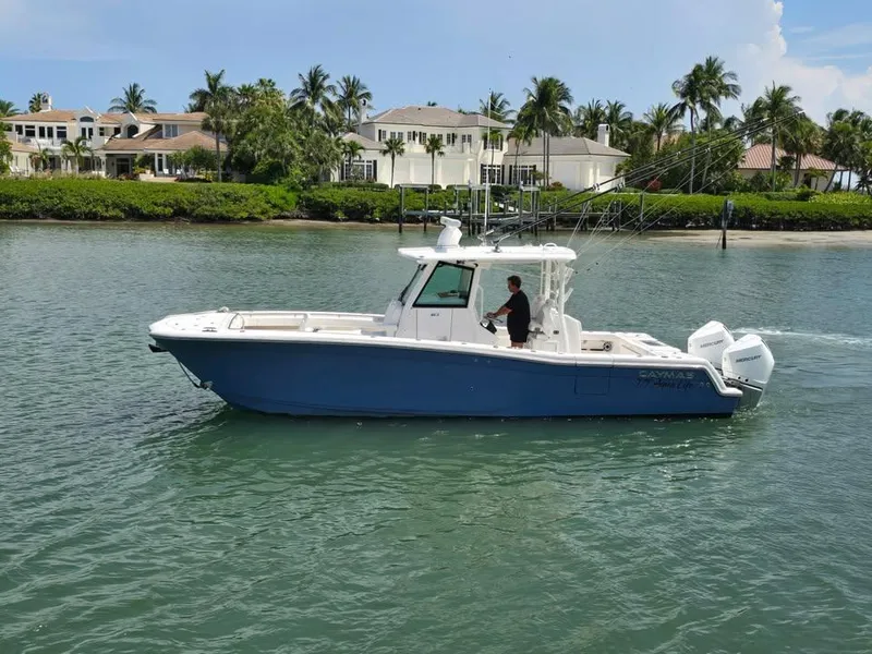 Slide: The Image of 2023 Caymas 30 CT boat cruising on a scenic waterway near luxury homes. - 3