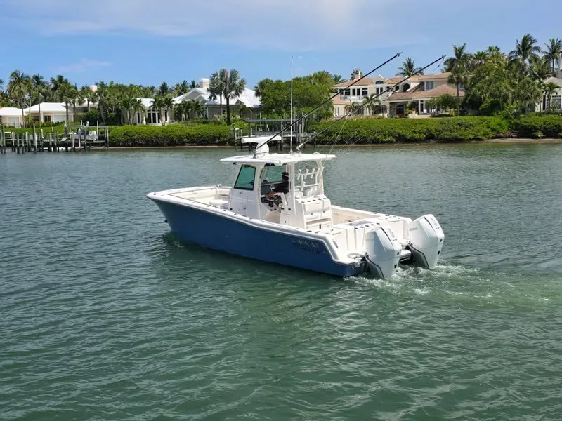 Slide: The Image of 2023 Caymas 30 CT boat cruising on a scenic waterway near luxury homes. - 7