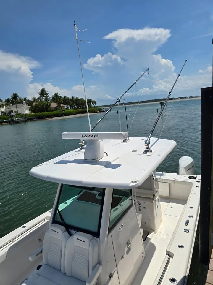 Slide: The Image of 2023 Caymas 30 CT boat docked, featuring Garmin equipment and fishing rods, under a clear sky. - 8