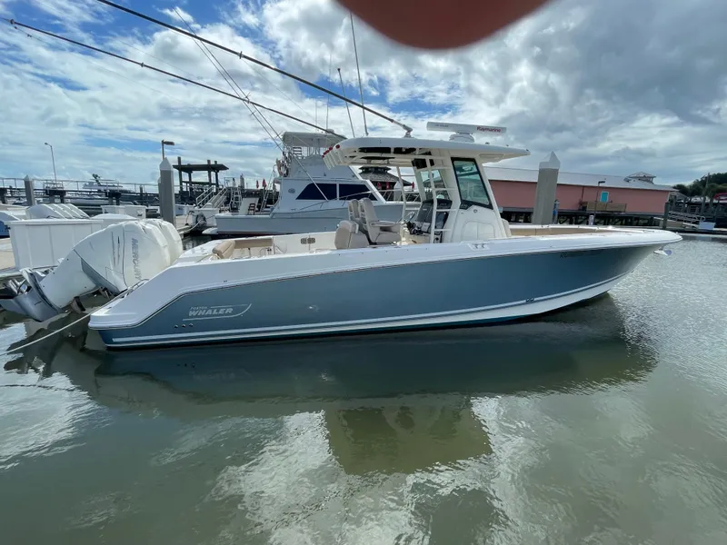 The Image of 2018 Boston Whaler 330 Outrage boat docked in marina under cloudy sky. - 0