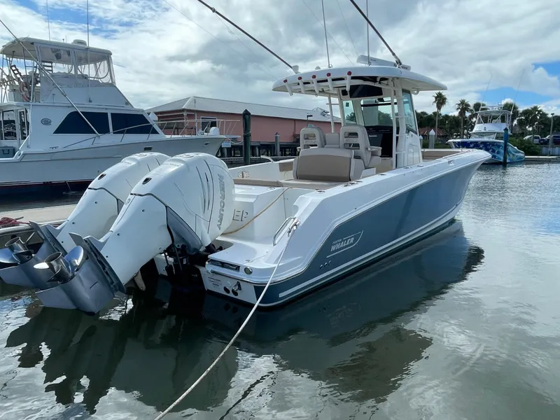 Slide: The Image of 2018 Boston Whaler 330 Outrage boat docked with twin engines, under cloudy sky. - 1