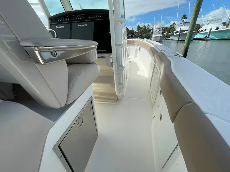 Slide: The Image of 2018 Boston Whaler 330 Outrage interior with seating and control panel, docked at marina. - 11