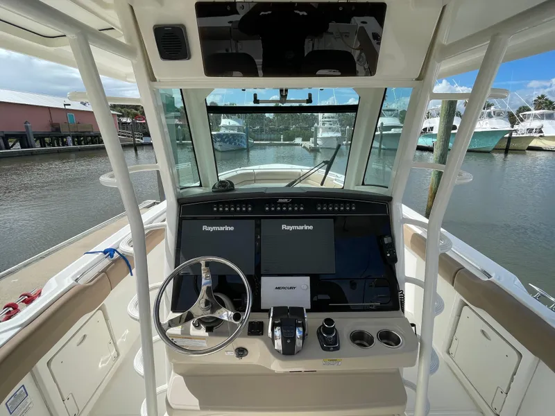 Slide: The Image of 2018 Boston Whaler 330 Outrage helm with dual Raymarine displays and steering wheel. - 13