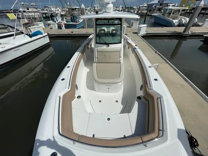 Slide: The Image of 2018 Boston Whaler 330 Outrage boat docked at marina, showcasing spacious deck and seating. - 17
