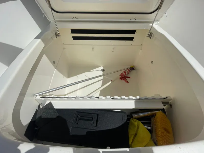 Slide: The Image of Storage compartment of 2018 Boston Whaler 330 Outrage, featuring cleaning tools and an American flag. - 19