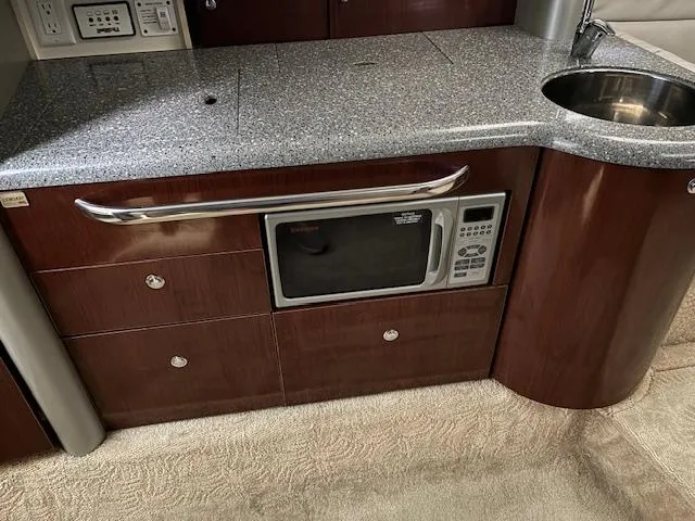 Slide: The Image of 2005 Formula 400 SS yacht interior with kitchenette, featuring microwave, sink, and wooden cabinetry. - 13
