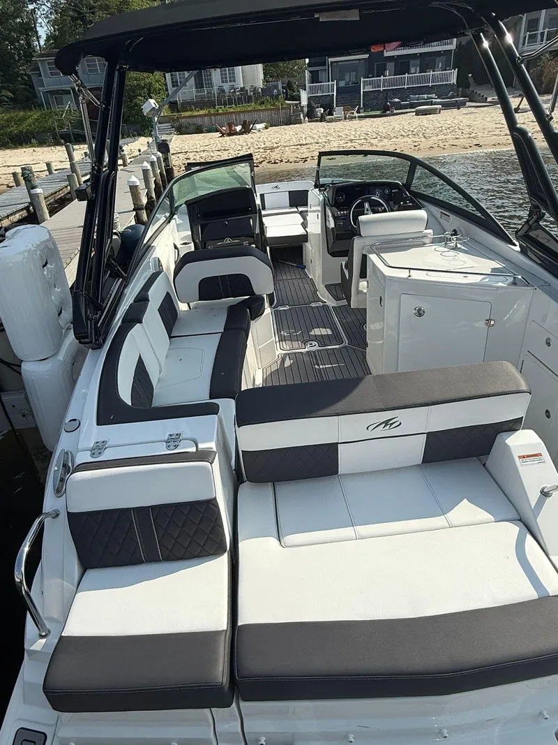 Slide: The Image of 2023 Monterey M65 boat with sleek seating, docked by a sandy beach. - 13