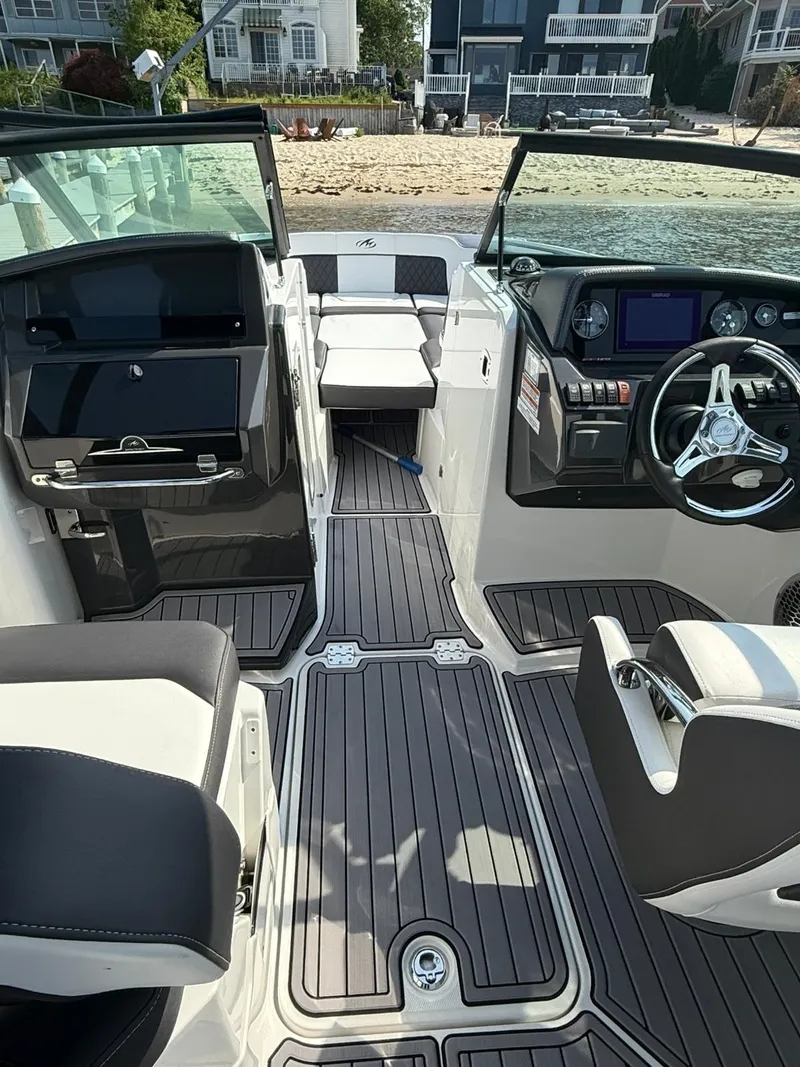Slide: The Image of 2023 Monterey M65 boat interior with modern dashboard and seating, docked near waterfront homes. - 18