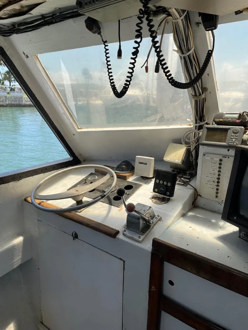 Slide: The Image of 1983 Commercial Hull #1 Key West boat cockpit with steering wheel and navigation equipment. - 10