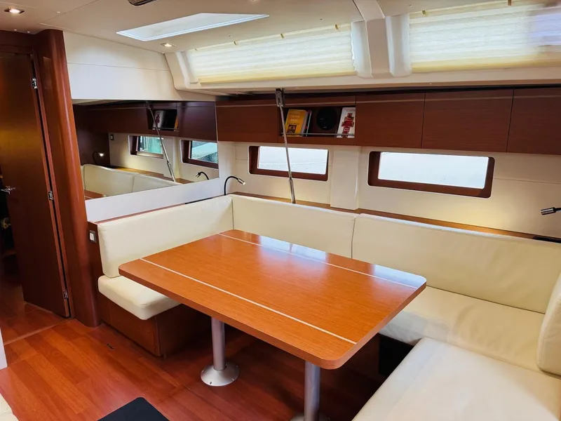 Slide: The Image of Interior of 2020 Beneteau Oceanis 51.1 yacht with wooden dining table and cream seating. - 19