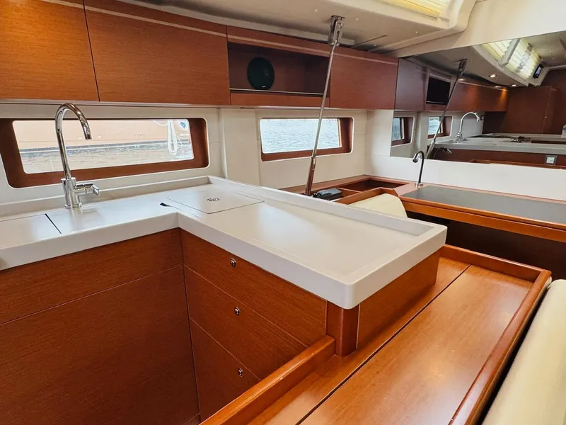 Slide: The Image of Interior of 2020 Beneteau Oceanis 51.1 yacht, featuring modern kitchen with wood cabinetry. - 32