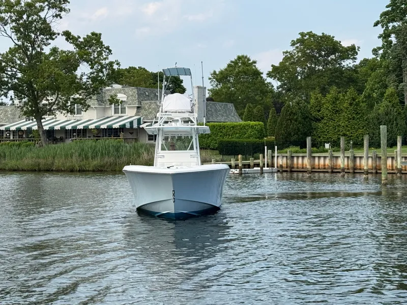 Slide: The Image of 2016 Invincible 39 Open Fisherman boat on calm water near a dockside house. - 9