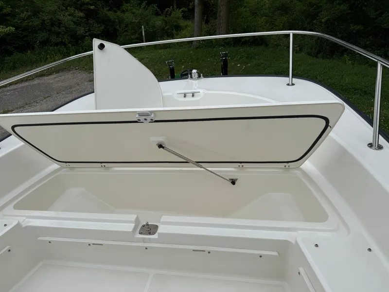 Slide: The Image of 2013 Boston Whaler 210 Montauk boat with open storage compartment, white interior, and railing. - 14