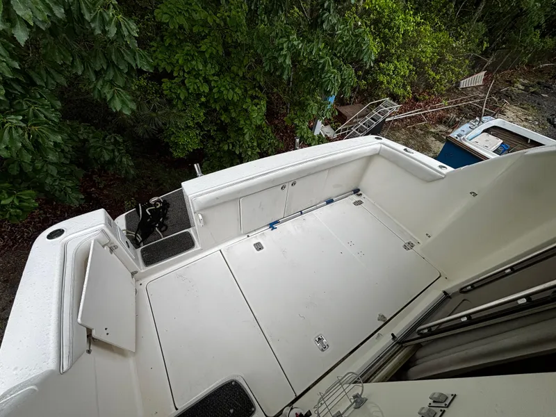 Slide: The Image of 2002 Silverton 330 Sport Bridge boat deck, surrounded by lush greenery. - 12