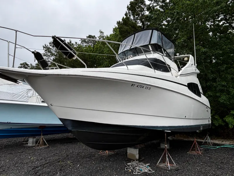 Slide: The Image of 2002 Silverton 330 Sport Bridge boat on stands, surrounded by trees. - 2