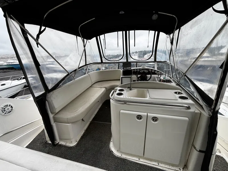 Slide: The Image of 2002 Silverton 330 Sport Bridge interior with seating and helm, featuring a covered cockpit. - 4
