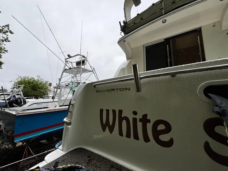 Slide: The Image of 2002 Silverton 330 Sport Bridge boat docked, featuring "White" on the stern. - 8