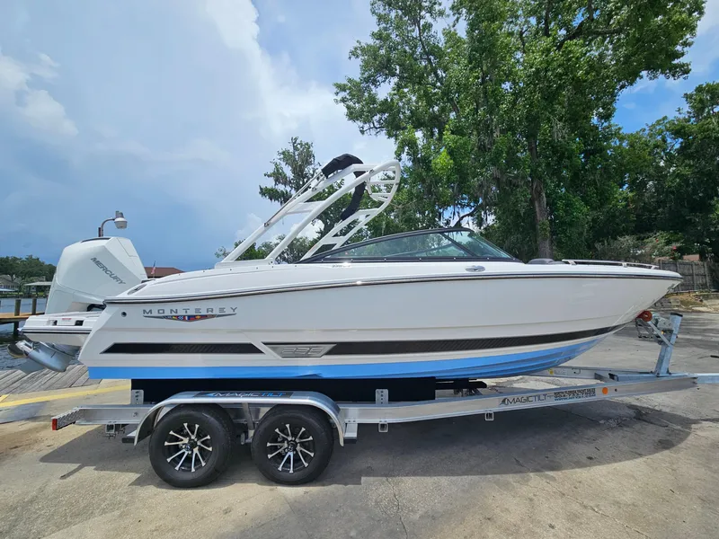 Slide: The Image of 2025 Monterey 235SS boat on trailer, parked outdoors with trees in background. - 1