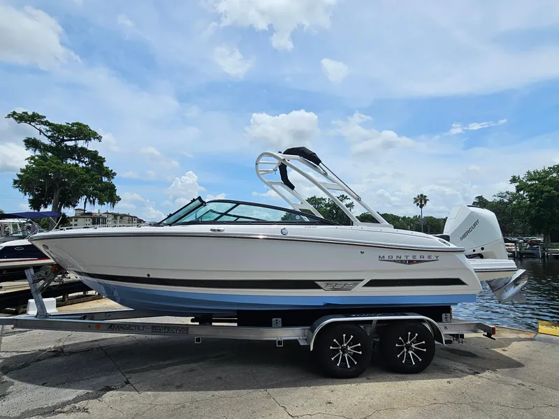 Slide: The Image of 2025 Monterey 235SS boat on trailer, parked near water under a partly cloudy sky. - 2