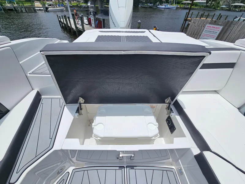 Slide: The Image of 2025 Monterey 235SS boat with open storage compartment, docked by a scenic waterfront. - 22